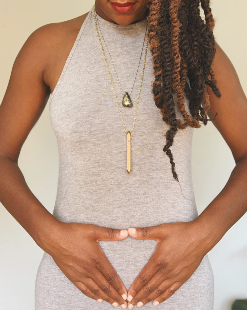 Natalie stands straight making the inverted triangle symbol with her hands over her womb a symbolism linked with females and the female pubic area.